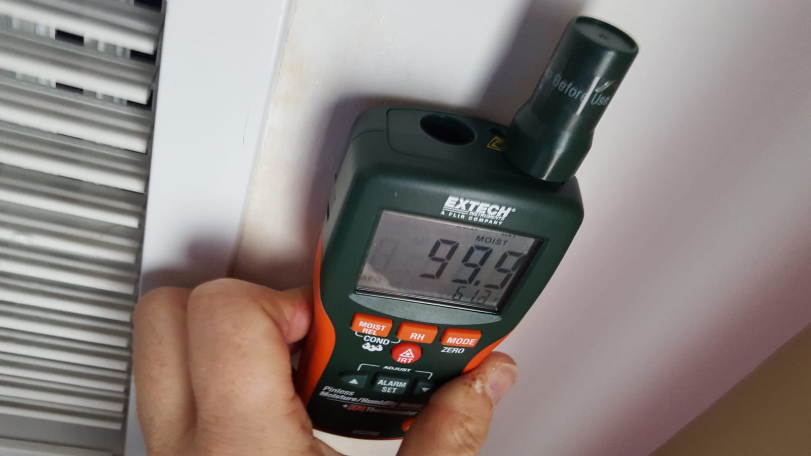 Moisture meter showing 99 percent reading at saturated HVAC vent