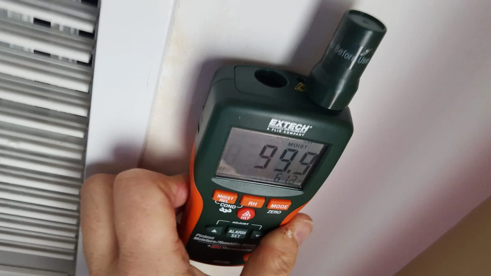 Moisture meter showing 99 percent reading at saturated HVAC vent