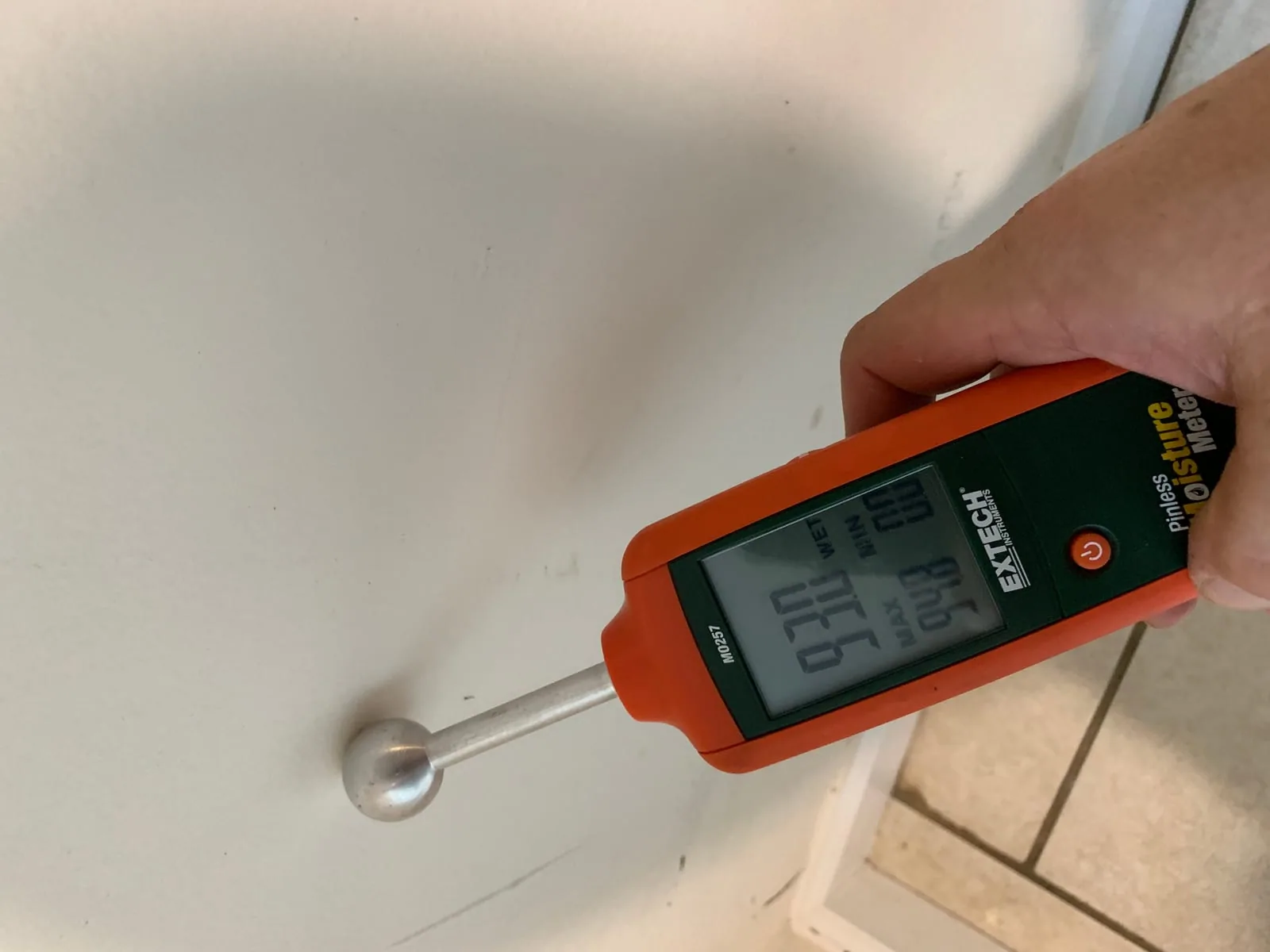Calibrated moisture meter taking a reading on a wet wall during a 911 Storm restoration job