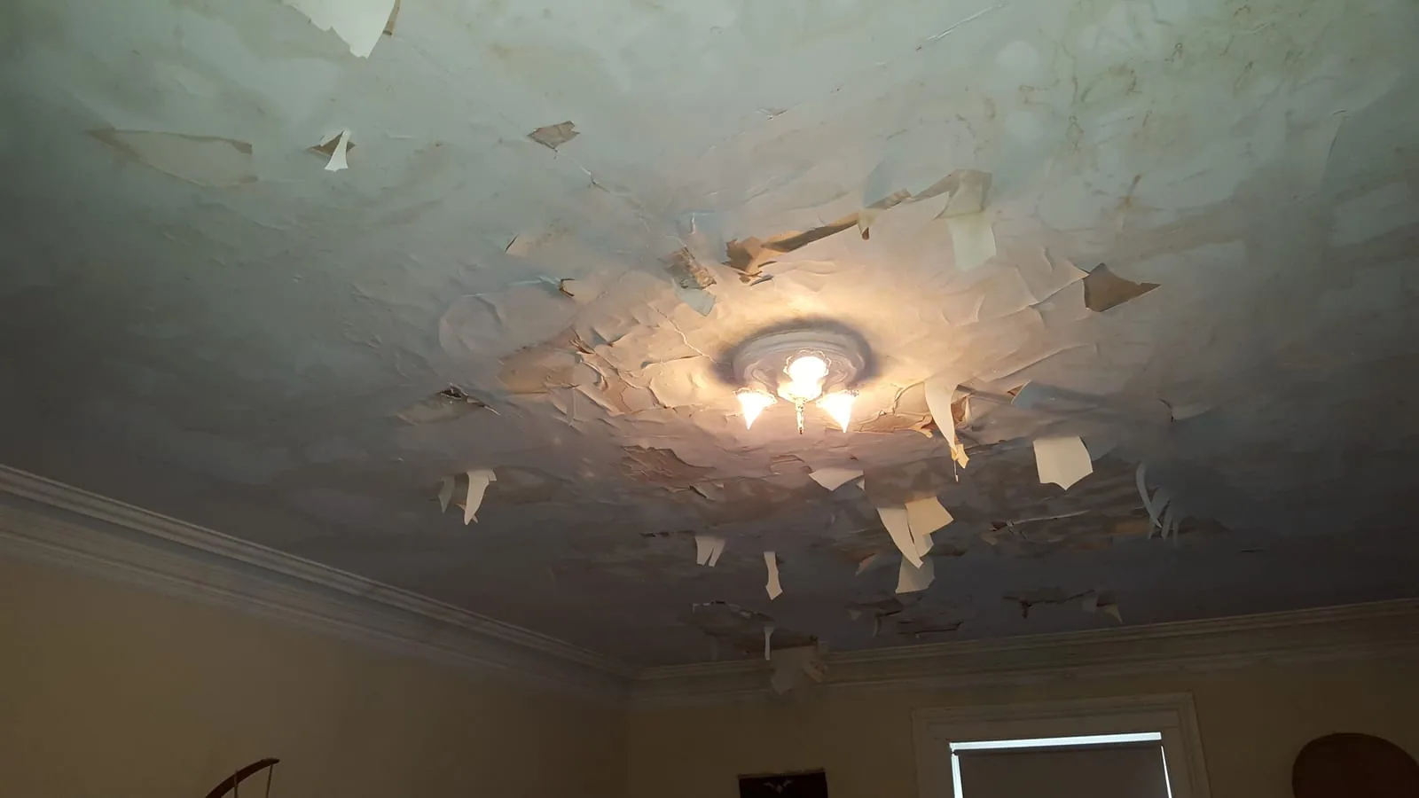 Water leaking through a plaster ceiling from a burst pipe in a Connecticut home during winter